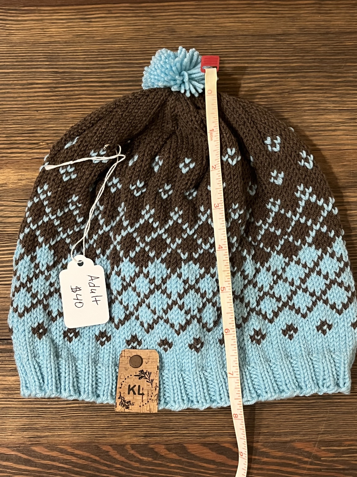 Adult hand knit wool hat shown with a measuring tape from top to brim