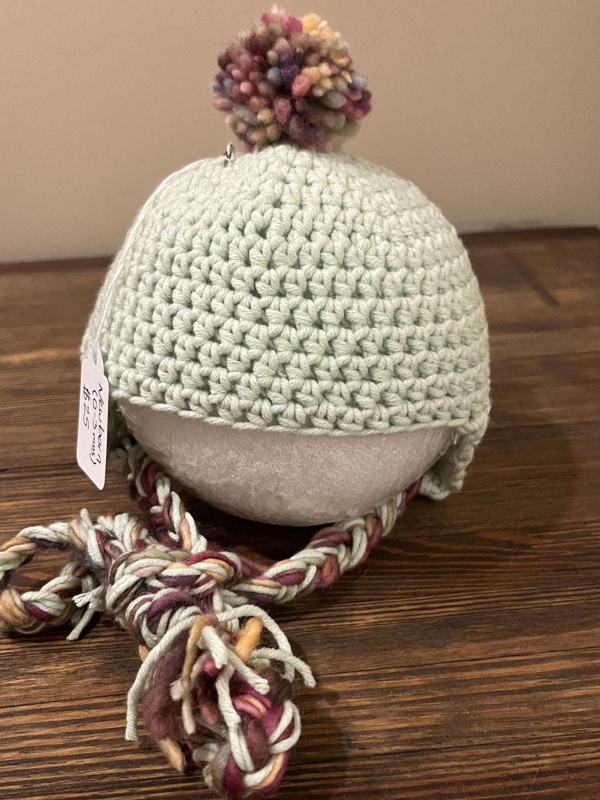 Front view of the mint green baby ear flap hat on a display form