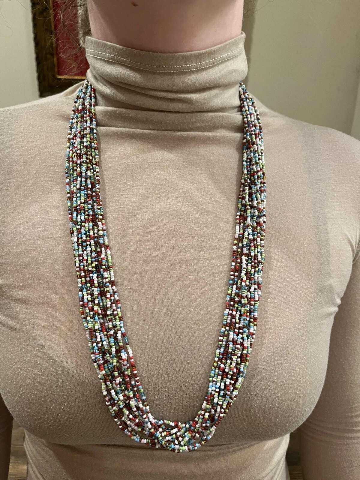 Multicolor fourteen-strand necklace with red, blue, green, and tan beads and a gold clasp