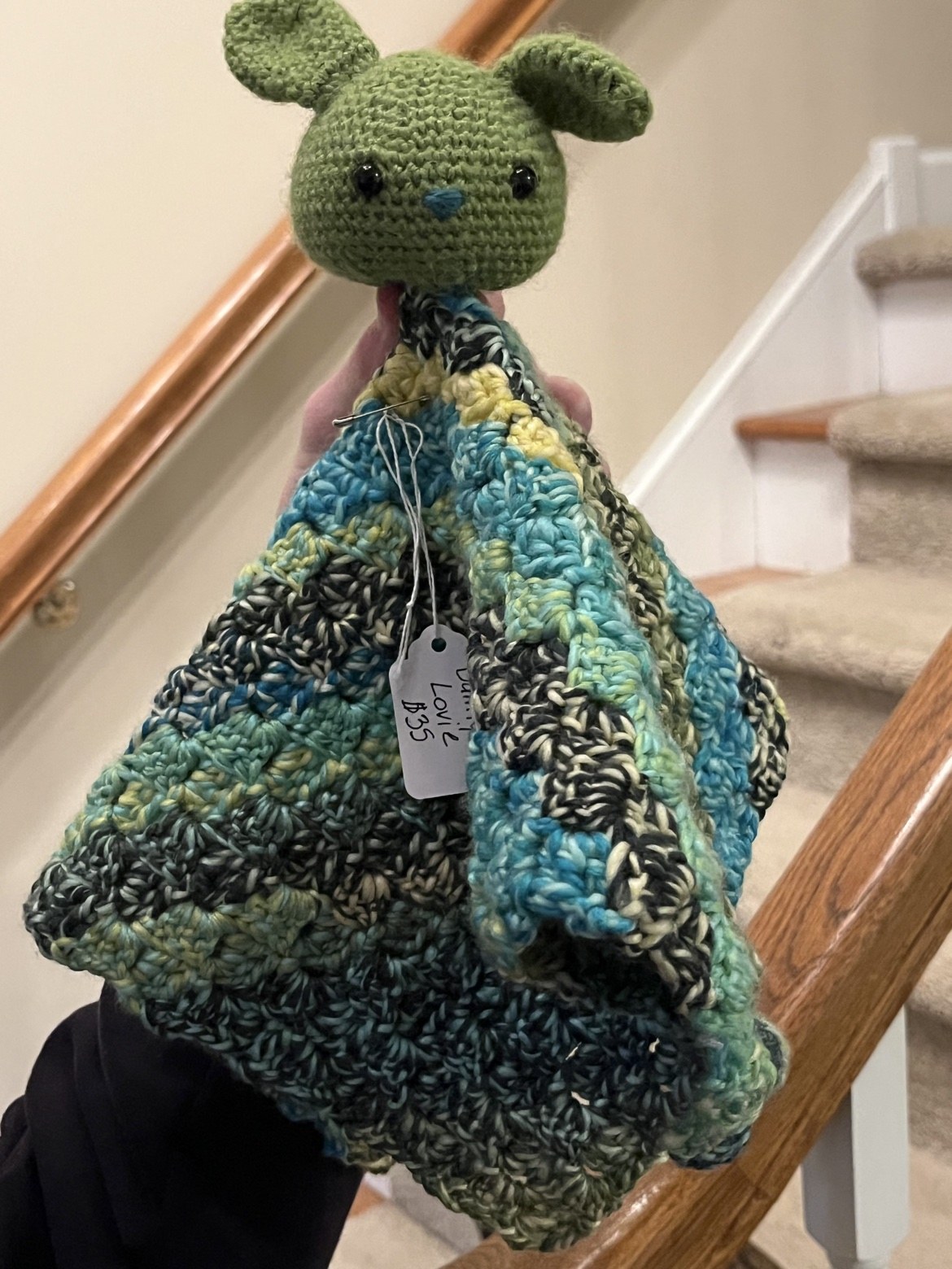Front view of the crochet bunny lovie held up to show the drape of the blanket