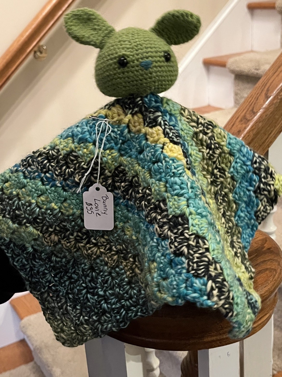 Crochet bunny lovie spread over a chair to show its multicolor blanket