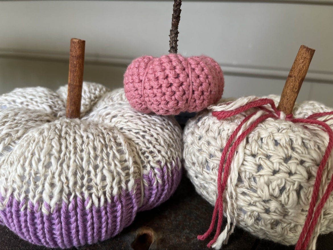 Close view of the purple, cream, and pink hand knit and crochet pumpkins