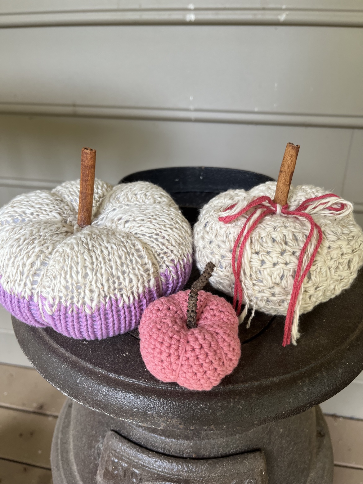 Purple, cream, and pink hand knit and crochet pumpkins stacked on a metal stand
