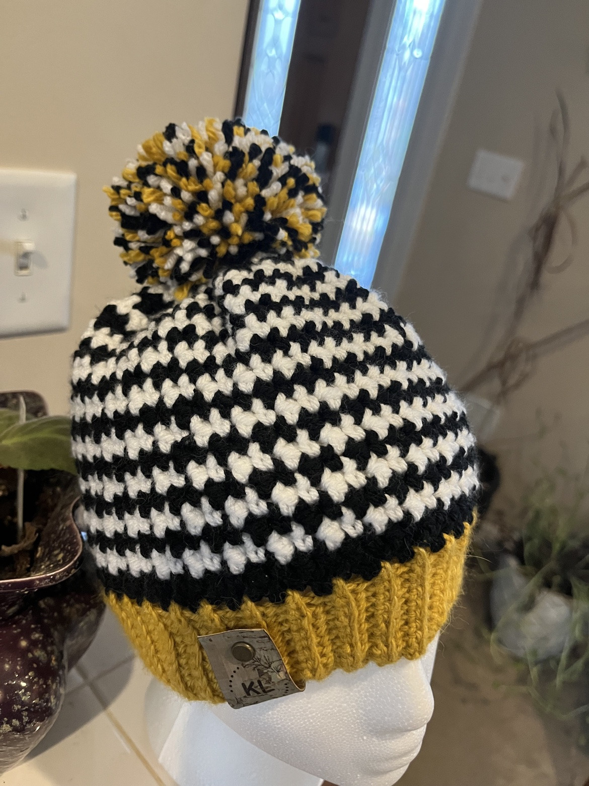 Black and cream patterned pom-pom hat with a mustard brim