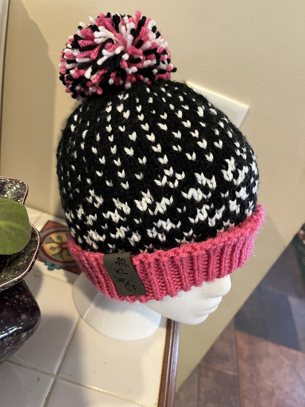 Black and white patterned pom-pom hat with a pink brim