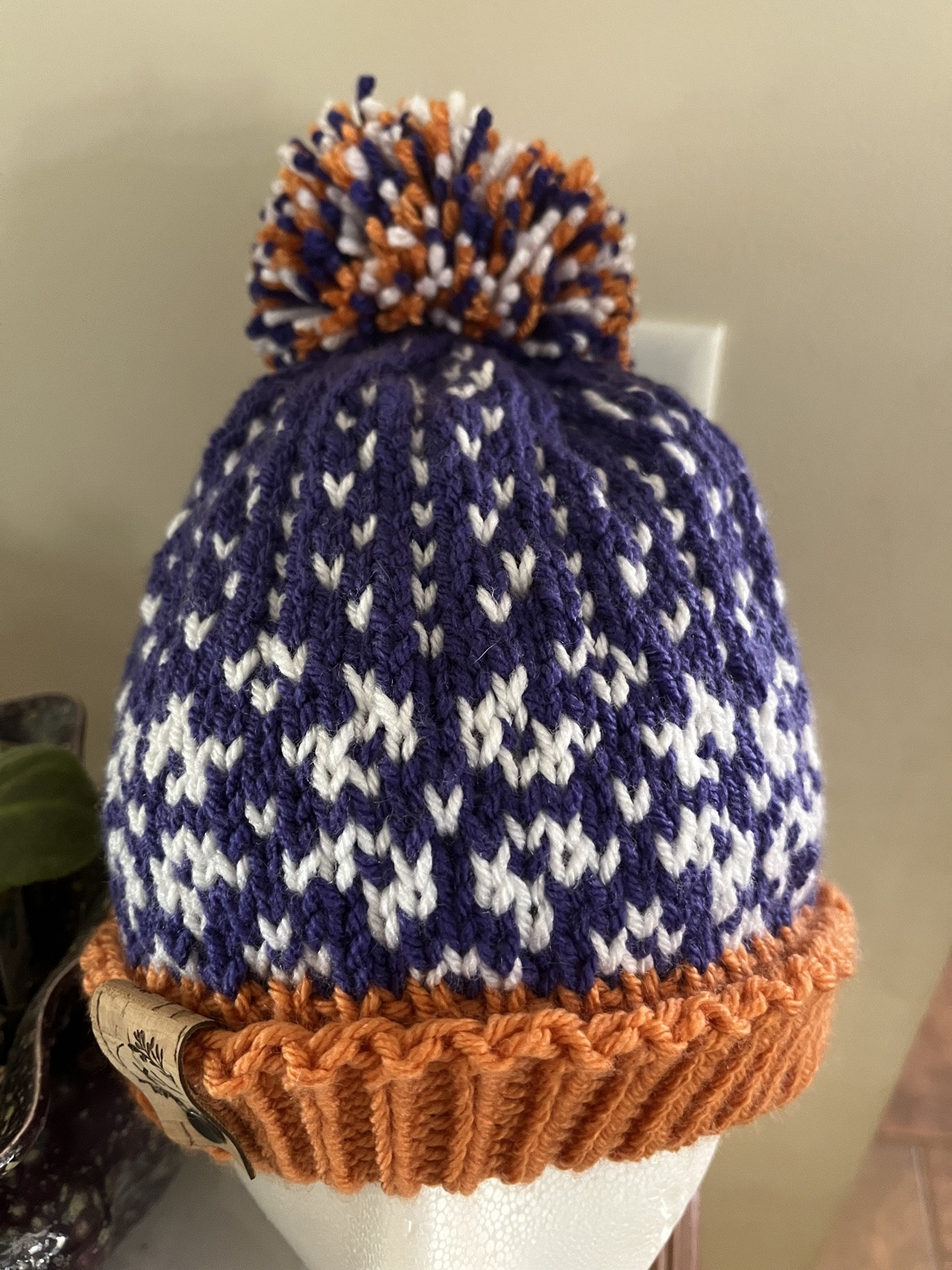 Navy and white patterned pom-pom hat with a rust brim