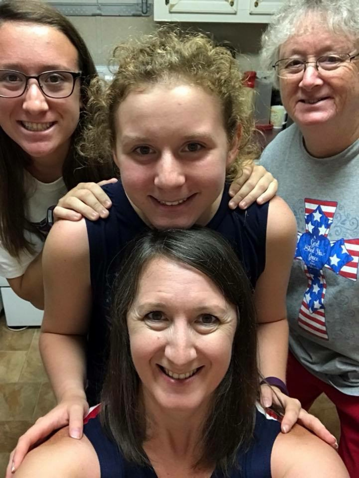 Four women smiling together in a kitchen