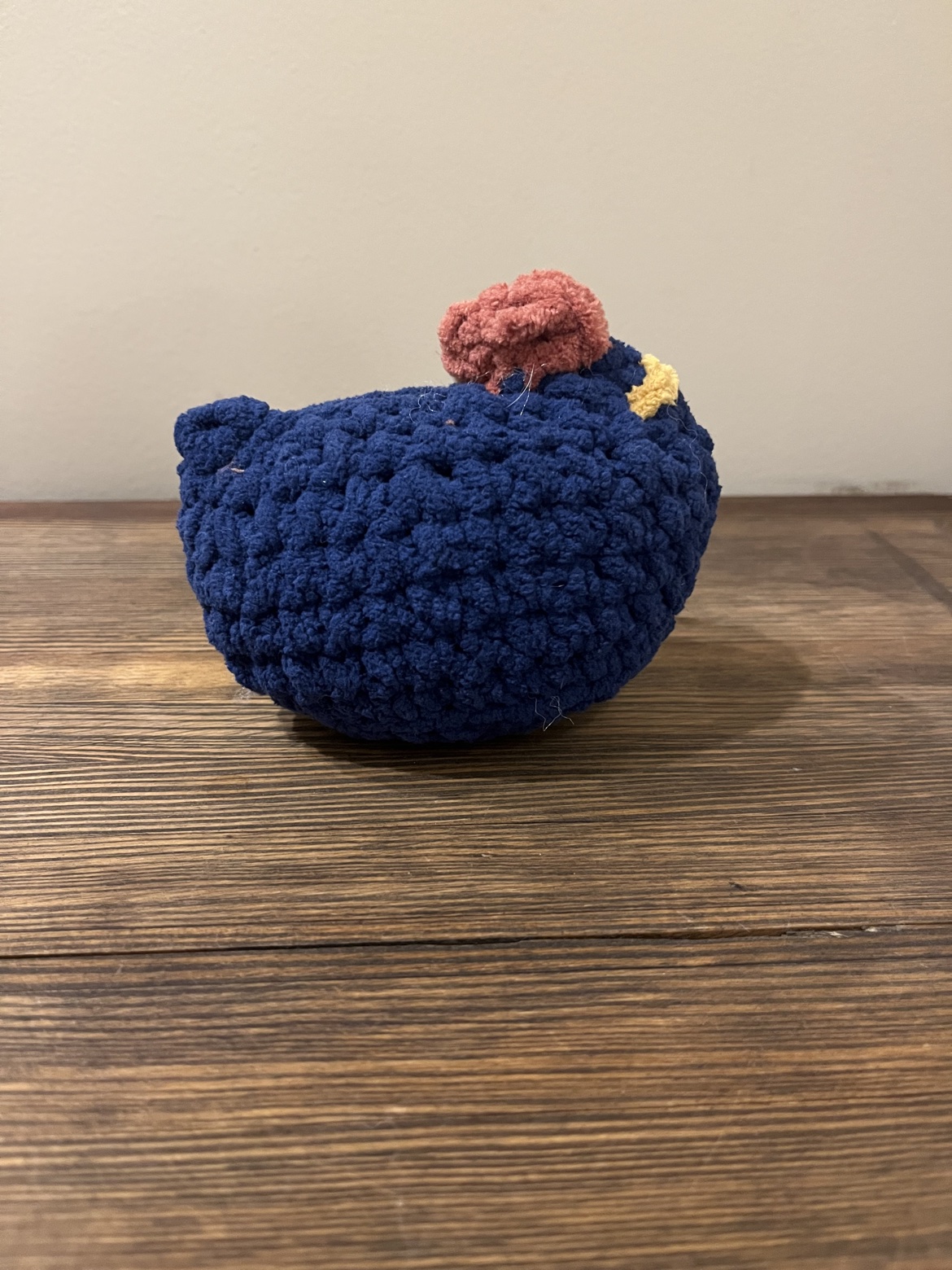 Side view of a crochet blue chicken with a rust comb and mustard beak