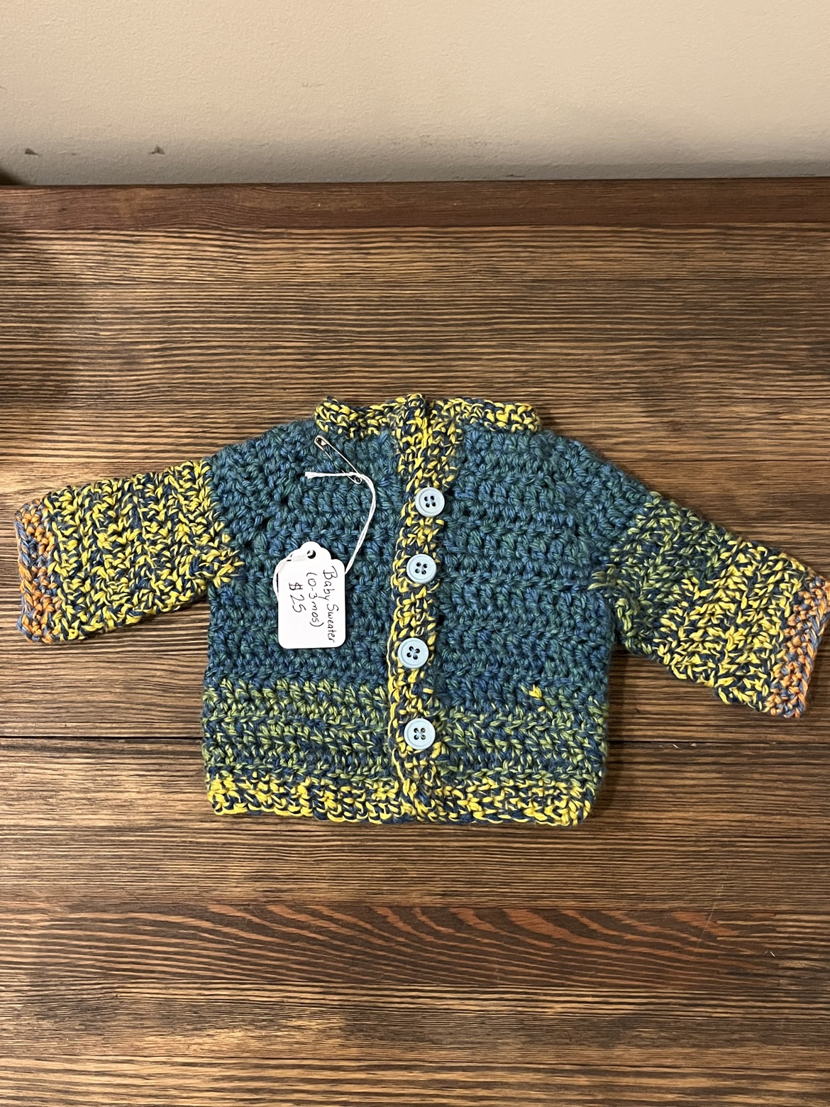 Crochet baby sweater in blue, orange, green, and yellow