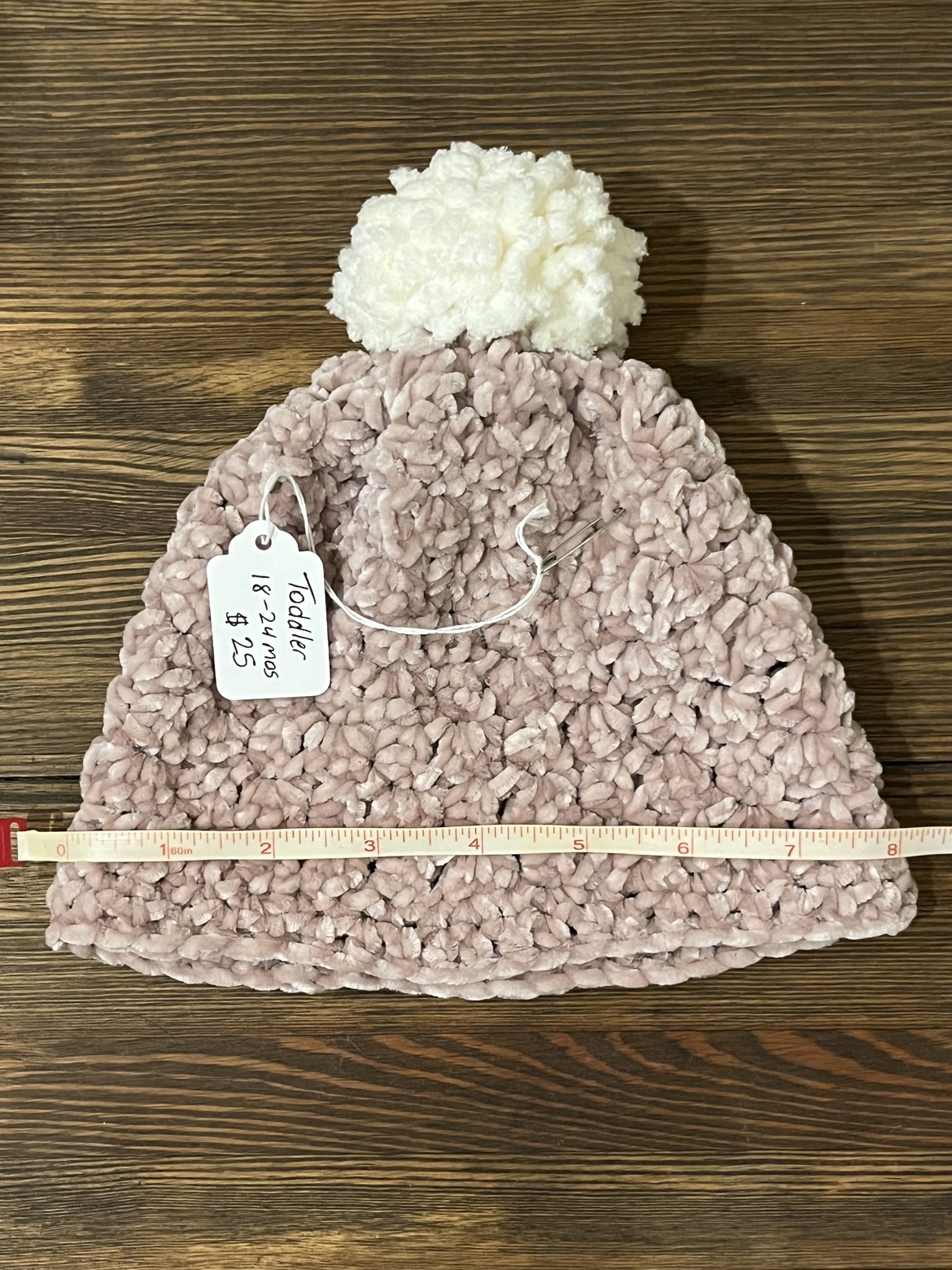 Crochet toddler hat shown with a measuring tape across its width