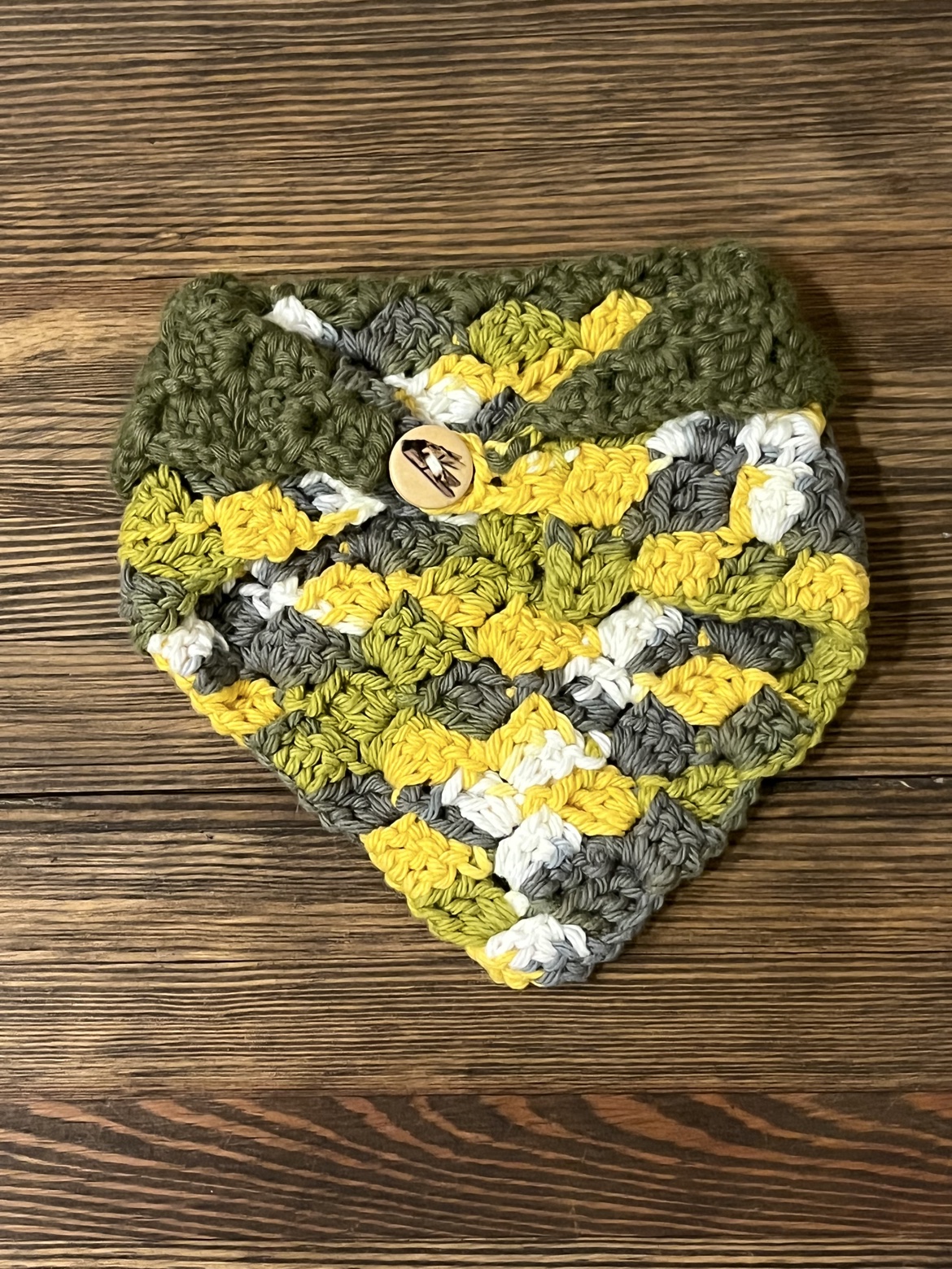 Reverse side of the dark green and multicolor crochet baby bib scarf showing the button closure