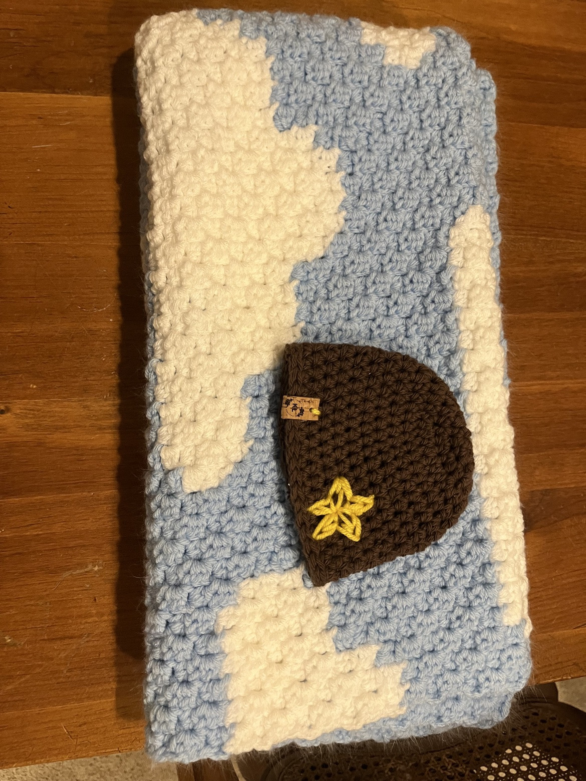 Pale blue and cream crocheted blanket with a small brown bear motif