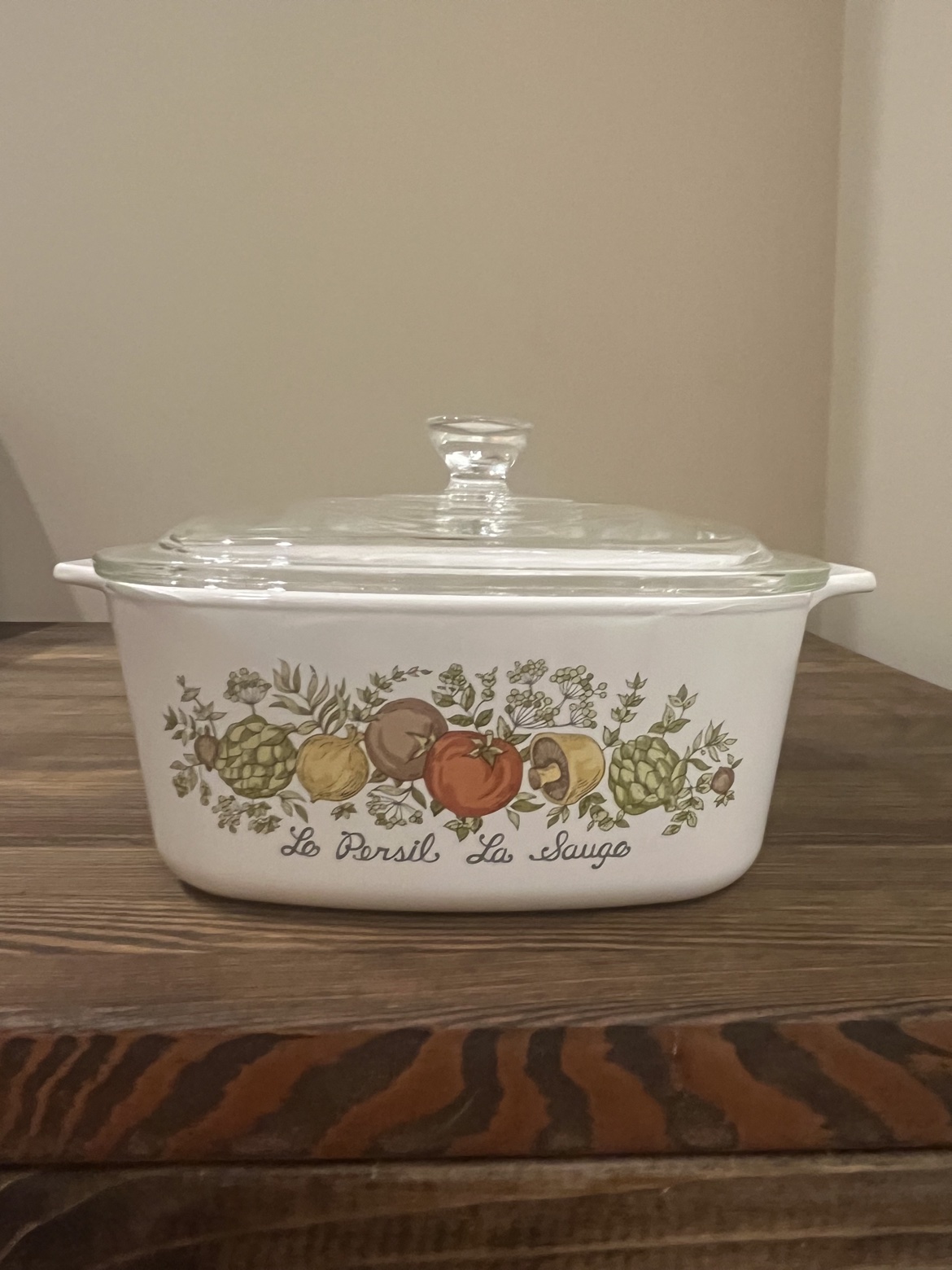 Vintage CorningWare casserole dish with glass lid, front view showing the vegetable pattern