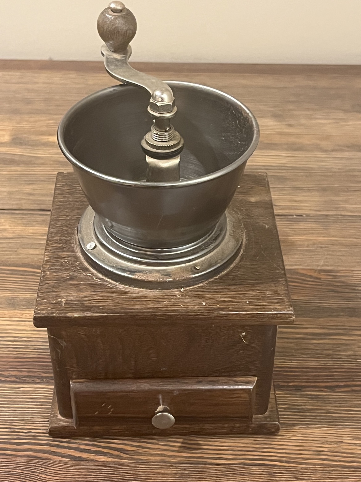 Vintage manual coffee grinder with wooden base and drawer, front view