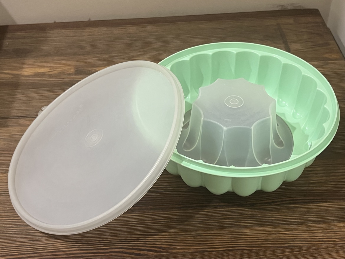 Mint green vintage Tupperware jello mold with the clear lid leaning beside it